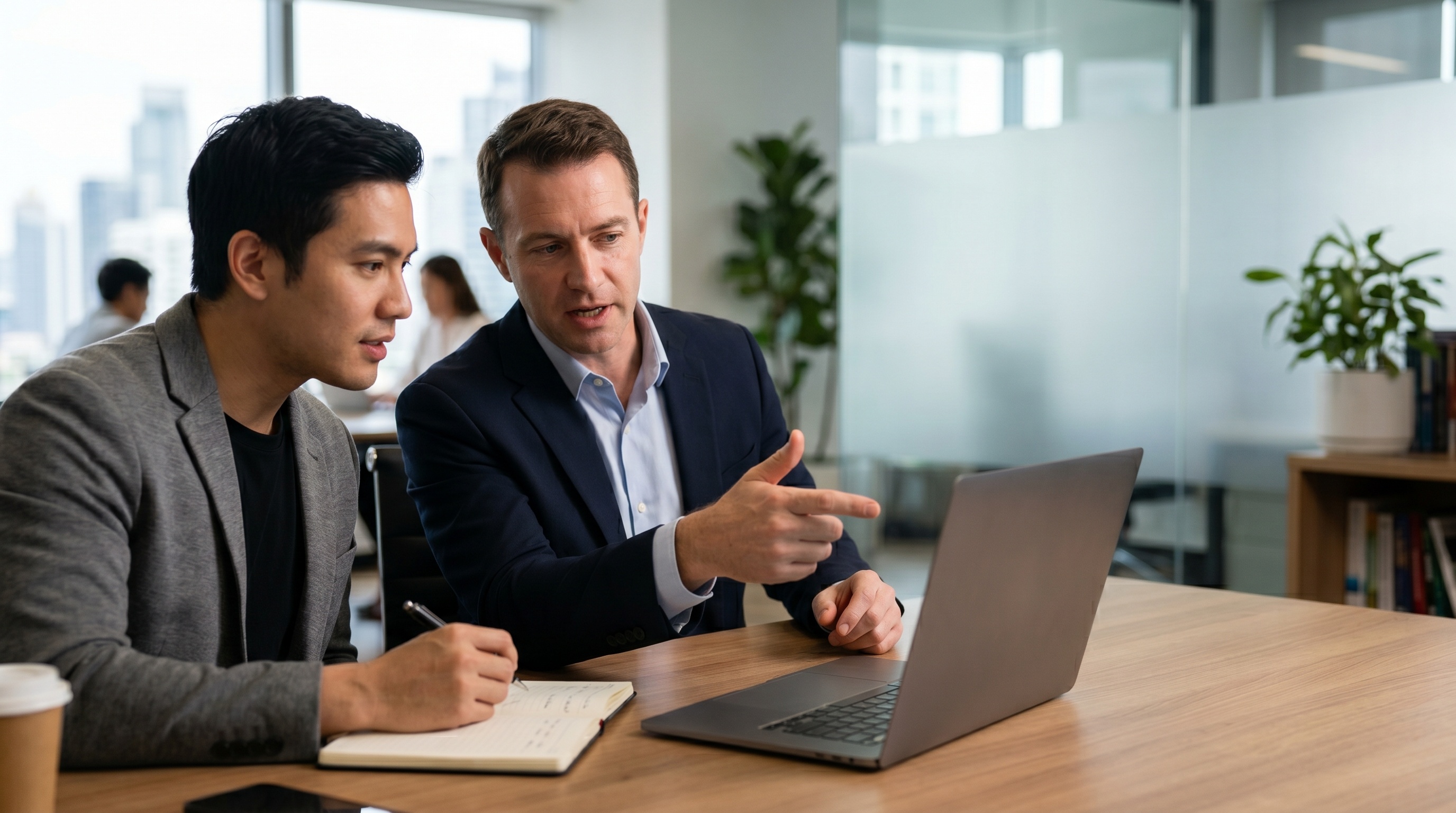 Two professionals reviewing information on a laptop and discussing a project.